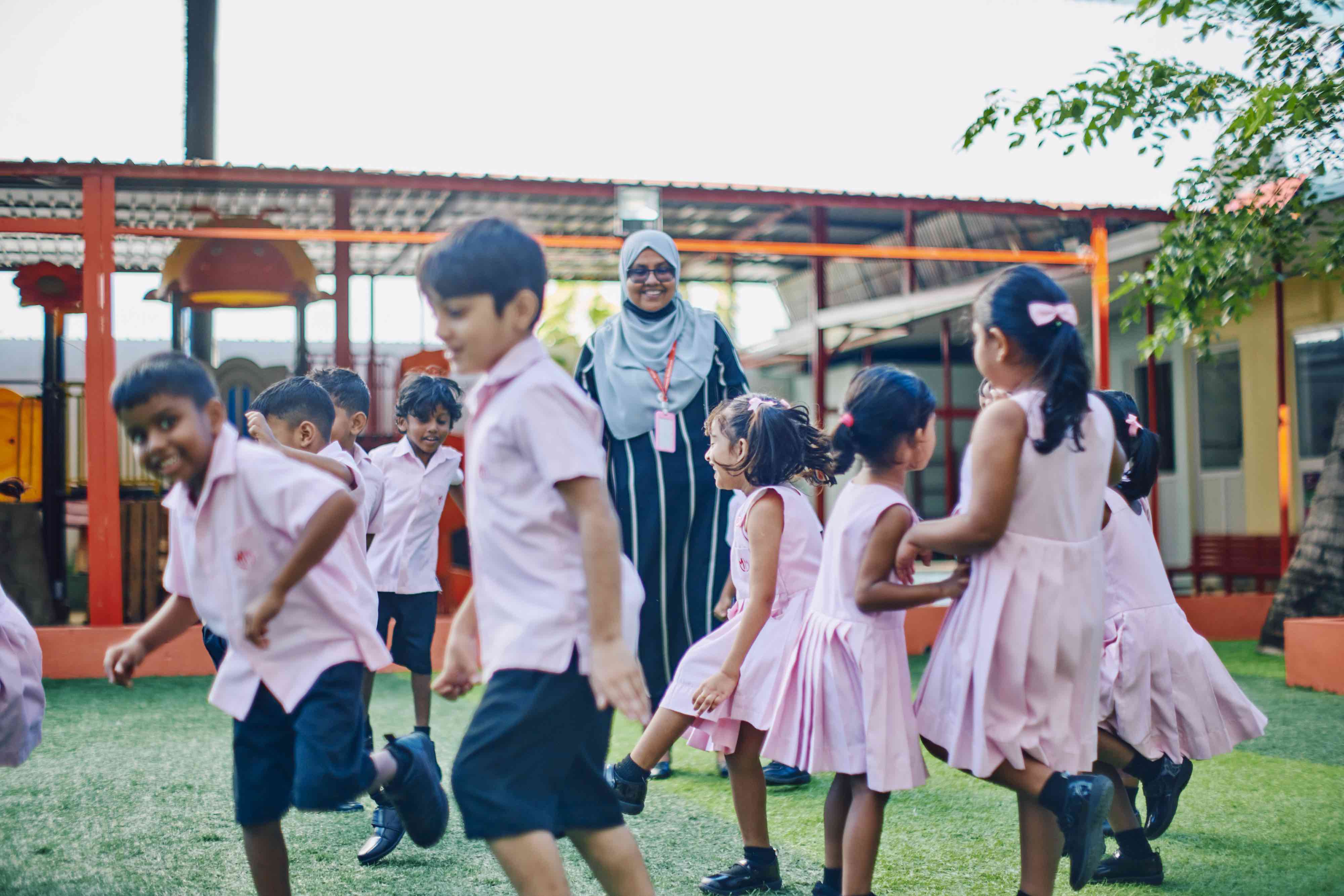 Children dancing in the school yard with their teacher