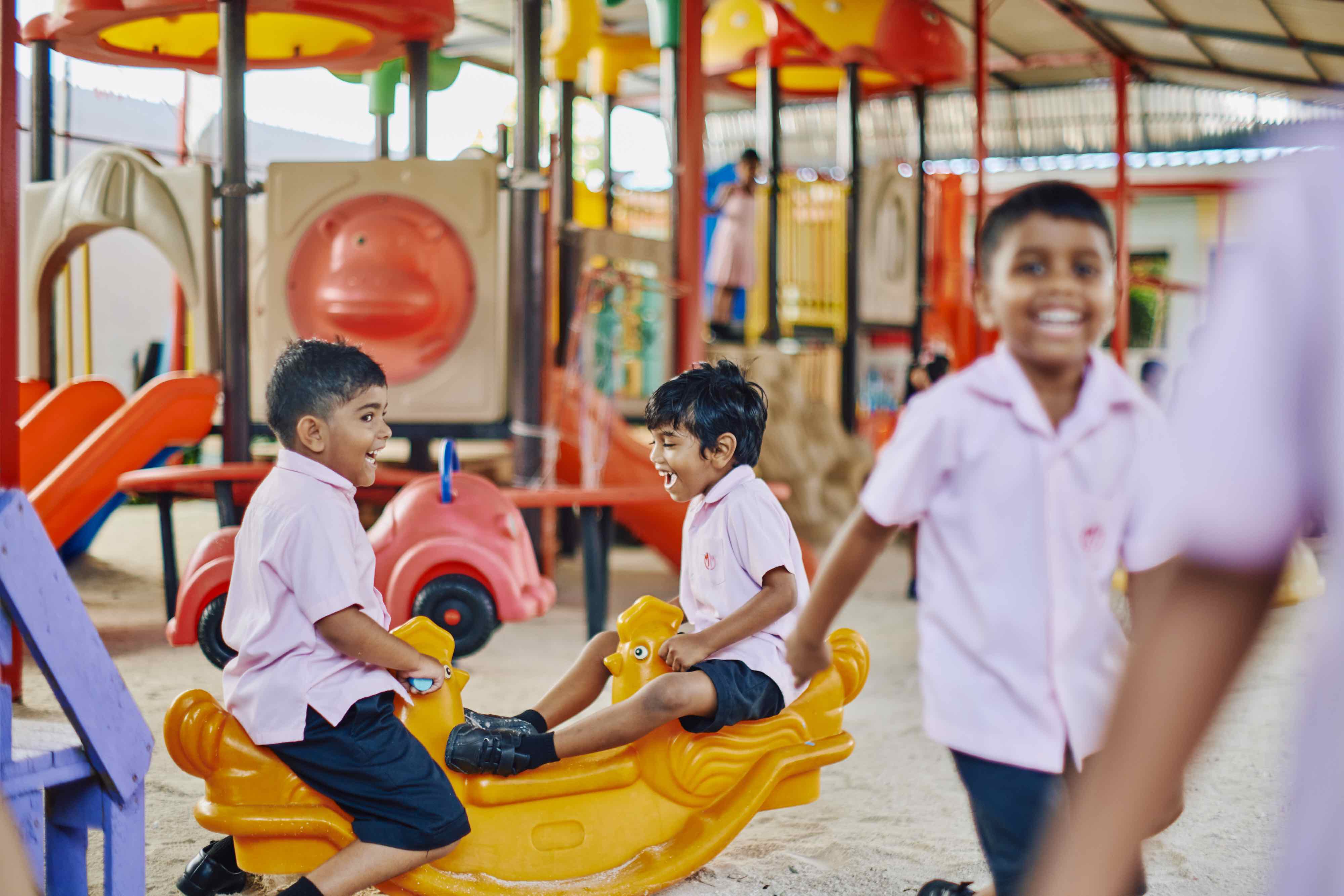 Boys laughing on the playground seesaw